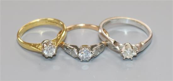 Three assorted 18ct gold and solitaire diamond rings including one set in white gold.